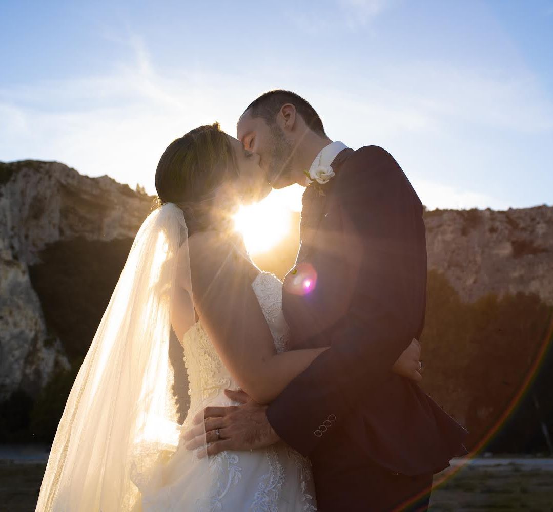 Couple de mariés qui s'embrasse au coucher du soleil